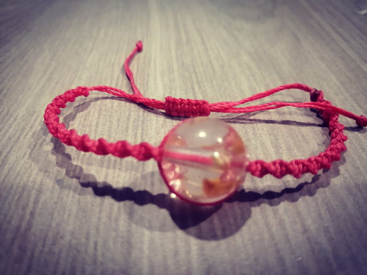 Pulsera tejida rosada con flores secas